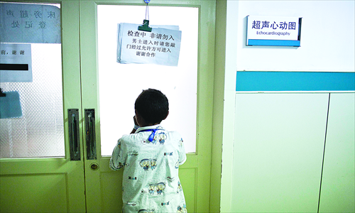 A Tibetan boy peeps through the window of an echocardiography room. Photo: Li Hao/GT
