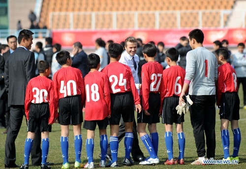  British soccer player David Beckham (C) shakes hands with students at the Qingdao Tiantai Stadium in Qingdao, east China's Shandong Province, March 22, 2013. Beckham visited Qingdao Jonoon Soccer Club as the ambassador for the youth football program in China and the Chinese Super League Friday. (Xinhua/Li Ziheng) 
