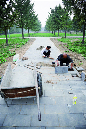 Construction workers pave the road on the green land on the northwest side of the Temple of Heaven Monday afternoon. Photo: Li Hao/GT
