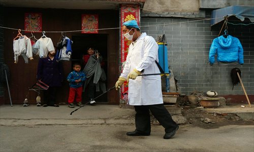 A Beijing medical staffer on Monday sprays disinfectant in a village that is home to a 4-year-old boy who was found to be a carrier of the H7N9 virus. Photo: CFP