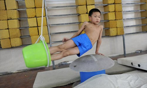 A boy trains with the help of a bucket in Zhangshan Sports School in Guangdong Province.
