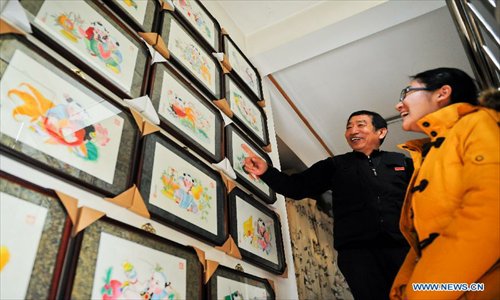 Huo Qingyou (L), a woodcut new year picture artist, introduces his works to a visitor in Yangliuqing town, north China's Tianjin Municipality, Dec. 28, 2012. In Yangliuqing, dubbed 