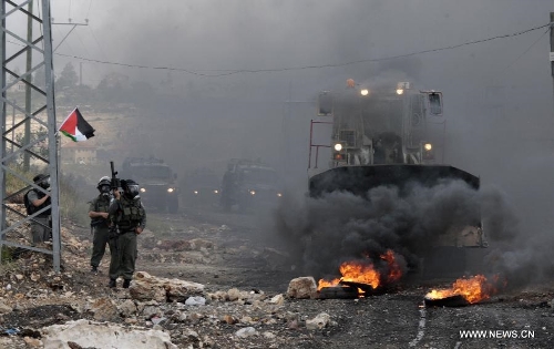 An Israeli bulldozer tries to remove burning tires from the road during a Palestinian protest against the expanding of Jewish settlements in Kufr Qadoom village near the West Bank city of Nablus on Apr. 5, 2013 (Xinhua/Nidal Eshtayeh) 