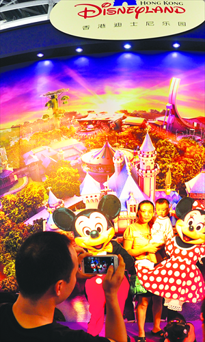 A man takes a picture of his family at the Hong Kong Disneyland booth at a recent tourism expo in Guangzhou. A new tourism law effective from October 1 this year bans forced shopping and hidden prices, and travelers have found that tourism fees have risen sharply for some overseas itineraries during the upcoming National Day holidays from October 1 to 7, Shanghai Evening Post reported Tuesday. Photo: CFP 