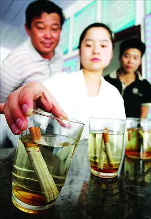A doctor illustrates to people the dangers of smoking by dunking cigarettes in water. Photo: CFP