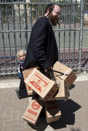 An Israeli man carries gas mask kits with his son as he leaves a distribution point in Jerusalem on Wednesday. Fearing that the fallout of a possible US strike on Syria could spill across their northern border and drag the Jewish state into the conflict, Israelis scurried to replace their old gas masks. Photo: AFP