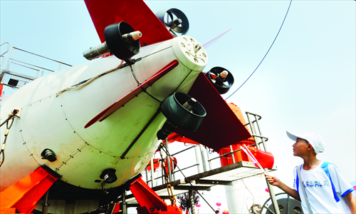A child takes a closer look at the Jiaolong on its mother ship, the Xiangyanghong-9, in Qingdao, Shandong Province Monday. The return of the ships marks the completion of its program of deep sea dives in the Pacific Ocean. Photo: CFP