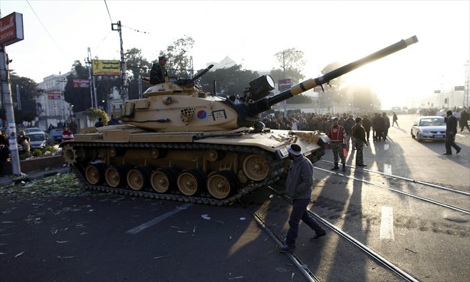 Egyptians walk past army tanks deployed near the presidential palace in Cairo after seven demonstrators died overnight in clashes between supporters and opponents of Islamist President Mohamed Morsi on Thursday. Morsi was expected to issue a statement to address the worst violence since his June election. Photo: AFP