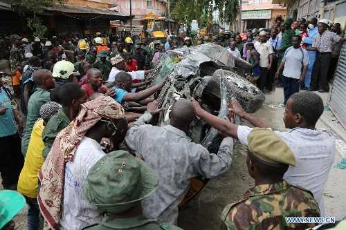 Rescuers move away a smashed car at the building collapse site in downtown Dar es Salaam, Tanzania, March 29, 2013. A 16-storey building on Friday morning collapsed in Dar es Salaam, with more than 60 people got trapped in the debris. No casualties have been reported as of noon local time. (Xinhua/Zhang Ping)
