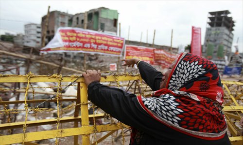 Lamia Begum, who lost her daughter in the factory collapse, cries holding on to a barbed-wire fence in front of Rana Plaza building on 24 June. Photo: CFP