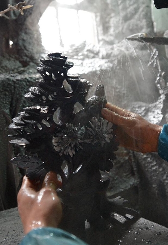 A craftsman named Hu Yongzhong washes a handicraft made of chrysanthemum stone in a workshop in Enshi, central China's Hubei Province, Jan. 12, 2013. 