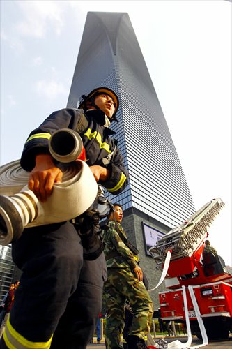 A firefighter hauls a firehose during a drill Thursday at the Shanghai World Financial Center. The firefighters practiced evacuation, search and rescue and high-rise firefighting during the drill. Photo: Yang Hui/GT