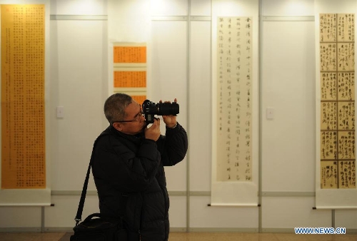A visitor takes photos of calligraphy works at the Hebei Province Museum in Shijiazhuang, capital of north China's Hebei Province, Jan. 20, 2013. Over 160 works were displayed at a running script calligraphy exhibition, which kicked off on Sunday. (Xinhua/Wang Xiao)
