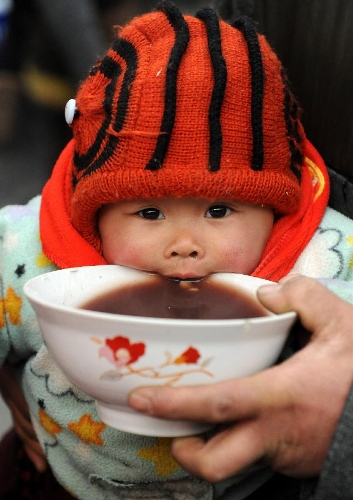  A child eats free porridge at White Horse Monastery in Luoyang, central China's Henan Province, Jan. 19, 2013. The White Horse Monastery distributed Laba porridge for free on Jan. 19, the eighth day of the 12th lunar month or the day of Laba Festival. The Laba Festival is regarded as a prelude to the Spring Festival, or Chinese Lunar New Year, the most important occasion of family reunion, which falls on Feb. 10 of this year. Drinking Laba porridge on the day of Laba is a traditional custom in China. (Xinhua/Li Bo) 