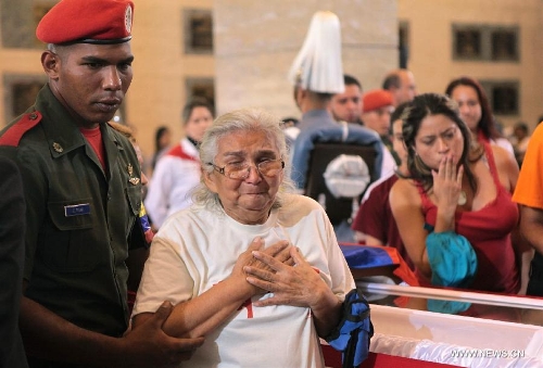 Image provided by the Presidency of Venezuela shows a woman react as visiting the coffin keeping the remains of late Venezuelan President Hugo Chavez, at the Military Academy of Venezuela in the city of Caracas, capital of Venezuela, on March 10, 2013. Venezuela's National Electoral Council (CNE) announced on Saturday after a special meeting of its Board of Directors that the presidential elections will be held on April 14.(Xinhua/Presidency of Venezuela) 