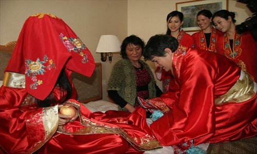 An American bridegroom, Lance Kawamoto, helps the bride Zhang Jie from Shandong Province to put on shoes during a traditional Chinese wedding in Beijing. Photo: IC