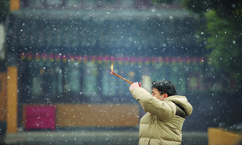 A man prays at a temple as it snows in Shanghai on Thursday ahead of Spring Festival. Preparations continue for lunar new year, which will celebrate the start of the Year of the Snake on Sunday. Photo: AFP