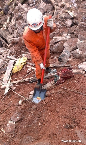 A rescuer works at the landslide site at Gaopo Village of Zhenxiong County, southwest China's Yunnan Province, Jan. 11, 2013. More than 10 residential houses with over 40 people were buried after a landslide happened at the village early Friday morning, according to local officials. Eight people have been confirmed dead by now. (Xinhua)&nbsp; 