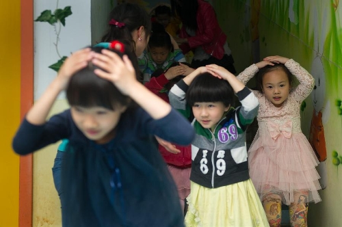 Children take part in an earthquake drill at a kindergarten in Hefei, capital of east China's Anhui Province, May 10, 2013, two days ahead of the Disaster Prevention and Reduction Day. The Disaster Prevention and Reduction Day was set in 2009, after a devastating earthquake hit Sichuan and neighboring Gansu and Shaanxi provinces on May 12, 2008, leaving 87,000 people dead or missing. (Xinhua/Du Yu)
