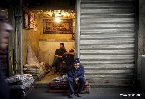 A seller waits for customers as he sits on carpets at Tehran's old main bazaar in downtown Tehran, Iran, on May 20, 2013. Economic condition of Iranian families is the core issue of the hopeful candidates for Iran's 11th presidential election, as the inflation rate of the Islamic republic, according to the Iranian Statistics Center, reached 29.8 percent in the first month of the current Iranian calendar year (March 21-April 20). (Xinhua/Ahmad Halabisaz) 