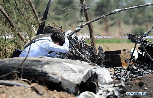 An investigator works beside the remains of a light plane after it failed to take off at Taoxian Airport in Shenyang, capital of northeast China's Liaoning Province, May 16, 2013. Three people on board were injured in the accident on Thursday. (Xinhua/Yang Qing)