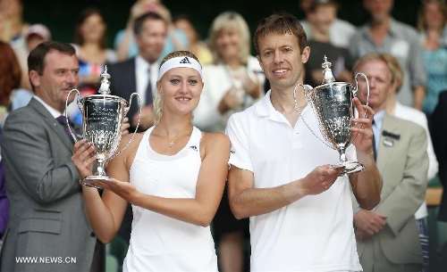 Daniel Nestor of Canada and Kristina Mladenovic (L) of France show their trophies during the awarding ceremony for the final of mixed doubles on day 13 of the Wimbledon Lawn Tennis Championships at the All England Lawn Tennis and Croquet Club in London, Britain, on July 7, 2013. Daniel Nestor and Kristina Mladenovic claimed the title by beating Bruno Soares of Brazil and Lisa Raymond of the United States with 2-1. (Xinhua/Wang Lili) 