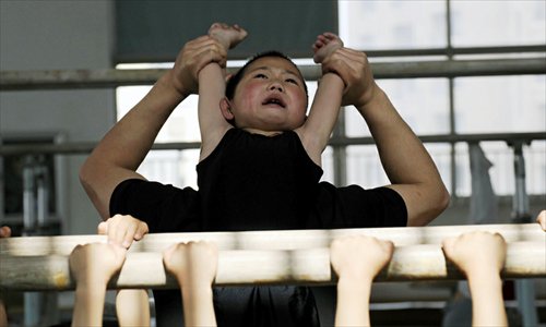 A boy stretches his back with the help of a coach at the Jiaxing Children's Sports School in Jiaxing, Zhejiang Province. Photos: ifeng.com