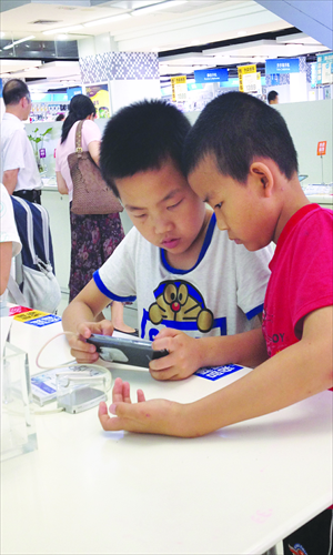 Kids play games on a smartphone in a department store in Guangzhou, South China's Guangdong Province. China's smartphone shipments totaled 78 million units in the first quarter of 2013, up 117 percent from a year ago, market intelligence firm IDC said in a statement on Monday. Photo: CFP 