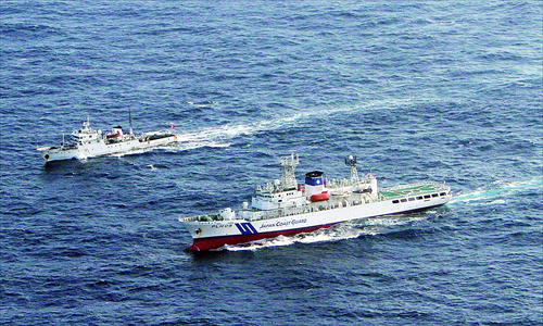 A Chinese patrol boat cruises near a Japan Coast Guard vessel in waters around the Diaoyu Islands. Japan summoned the Chinese ambassador on Wednesday as a diplomatic row flared up after three Chinese patrol boats approached a chain of islands at the center of a territorial dispute. Photo: AFP
