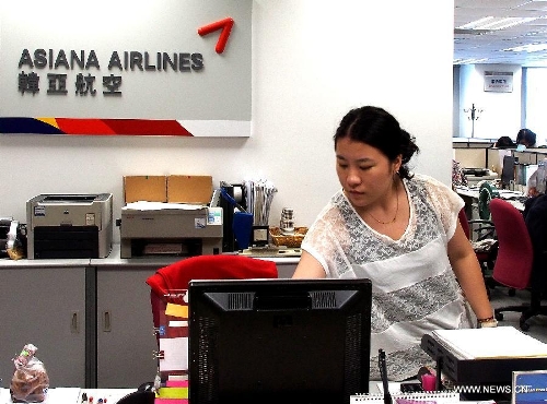 An employee works at the office of the Asiana Airlines to Shanghai, east China, July 7, 2013. A total of 141 Chinese citizens were among the 291 passengers aboard the Asiana Airlines flight that crash-landed at the San Francisco International Airport on Saturday, and 90 of the Chinese passengers in total departed from Shanghai via Seoul to the San Francisco airport in the U.S. All the two killed in the crash were identified to be Chinese women, South Korea's transportation ministry said Sunday. (Xinhua/Chen Fei)&nbsp; 