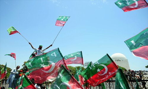 Supporters of cricket legend and chairman of Pakistan's Tehreek-e-Insaaf, or Movement for Justice party, Imran Khan wave party flags outside the mausoleum of Pakistan's founder Mohammad Ali Jinnah during a campaign rally in Karachi on Tuesday. Khan sustained head injuries and was rushed to hospital after falling off a lift taking him onto the stage for the election rally, his party said. Photo: AFP