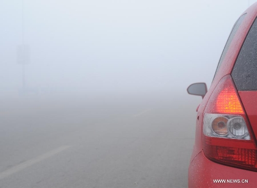  A car runs on a street in dense fog in Baoding, north China's Hebei Province, Jan. 12, 2013. Heavy fog hit many parts of Hebei Province on Saturday. The visibility was less than 200 meters in some areas. (Xinhua/Zhu Xudong)