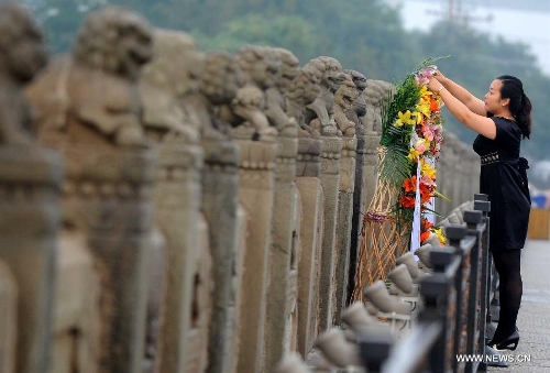 A woman presents a flower basket on the Lugou Bridge during a memorial event marking the 76th anniversary of 
