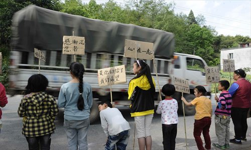 Students hold signs showing their gratitude to relief workers and volunteers near Miaoxi village, Lushan county on Wednesday. Photo: Li Hao/GT