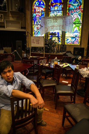 An employee sits in the restaurant with a white banner reading 