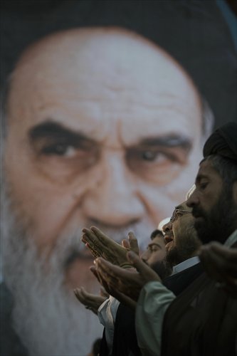 Clerics pray as they stand in front of a huge portrait of Iran's late leader Ayatollah Khomeini, during a ceremony to mark the death anniversary in Khomeini's shrine in southern Tehran. Photo: IC