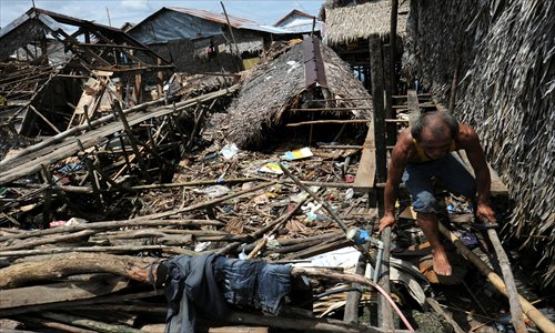 A resident walks through a wooden bridge near damaged homes after a 7.6 magnitude earthquake on August 31 hit the town of General MacArthur, eastern Samar province, in the central Philippines on Sunday. Families returned to their quake-devastated homes Sunday, ignoring government warnings to relocate away from danger zones. Photo: AFP 