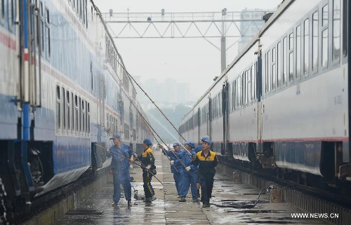 Staff members from the maintenace crew clean a train in Chengdu, capital of southwest China's Sichuan Province, July 8, 2013. Known as the