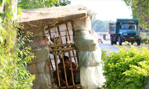 By the roadside of G209 at Shapu town in Liuzhou, Guangxi Zhuang Autonomous Region, Liu Lingchao eats his lunch in his movable house on Wednesday. Liu, 38, from Longcheng village of Rongan county, Guangxi, left Shenzhen, Guangdong Province, five years ago to walk to his hometown, and has walked roughly 1,000 kilometers. His home is made of bamboo and plastic, and he refused other people's help and earns money by collecting plastic bottles and other waste materials. Photo: CFP