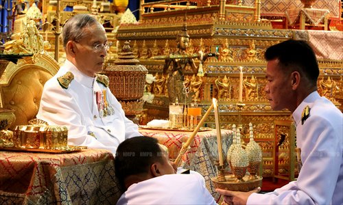 Thai King Bhumibol Adulyadej lights a candle on Monday as he marked the 64th anniversary of his coronation at the Klai Kanwon Palace. Photo: AFP