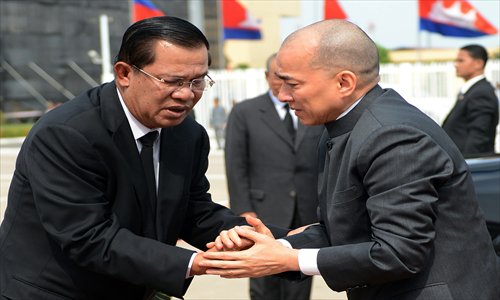Cambodian King Norodom Sihamoni (R) shakes hands with Prime Minister Hun Sen (L) before departing for China at Phnom Penh International airport on Monday. Cambodia's former king Norodom Sihanouk, whose life mirrored the turbulent history of his nation where he remained a revered figure, died in Beijing on Sunday. Photo: AFP