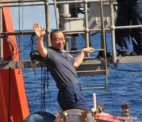 Zhou Huaiyang, professor of the School of Ocean and Earth Science at Tongji University, waves before entering China's manned deep-sea submersible Jiaolong aboard the Xiangyanghong 09 in South China Sea, June 18, 2013. The Jiaolong manned deep-sea submersible on Tuesday carried its first scientist Zhou Huaiyang as crew member during a deep-sea dive. Jiaolong left east China's city of Jiangyin on June 10 for its first voyage of experimental application. The 113-day-long mission will include experiments on Jiaolong's positioning system, as well as deep-sea ecological and geological surveys in the South China Sea, biological surveying and geological sampling in the Pacific Ocean. (Xinhua/Zhang Xudong)