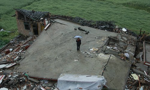 Huang Shenglian, a villager from Longmen township in the quake-hit city of Ya'an, Sichuan Province, stands on the ruins of her house on Tuesday. Photo: IC
