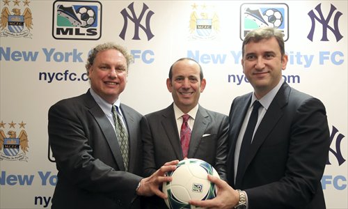New York Yankees president Randy Levine (left), MLS commissioner Don Garber (center) and Manchester City chief executive Ferran Soriano pose for photographs at the MLS headquarters in New York on Tuesday. Photo: IC
