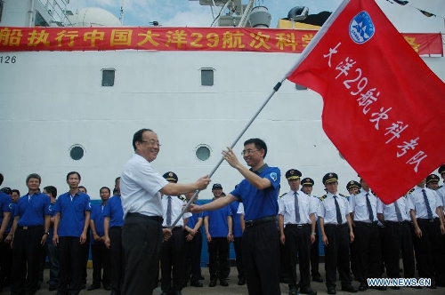 Wang Fei (L), director of China Ocean Mineral Resources Research and Development Association, confers a flag to a team member beside Haiyang-6, a Chinese research vessel, at a dock in Guangzhou, capital of south China's Guangdong Province, May 28, 2013. An expedition team of 96 members aboard Haiyang-6 set out for the Pacific Ocean Tuesday to carry out a five-month survey on undersea mineral resources. (Xinhua/Liang Zhiwei) 