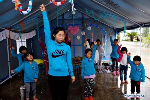 Volunteer Zhou Lanqi leads children during a dance class in a temporarily-erected tent in Lushan County, southwest China's Sichuan Province, May 17, 2013. More than 100 children frequently participate in extra-curricular activities at this temporary school, which was opened on April 29 by volunteers and provides reading, painting and dancing classes to local children. The county was jolted by a 7.0-magnitude earthquake on April 20. (Xinhua/Liu Xiao) 