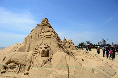 People walk past sand sculptures along the beach in Nanhai New District in Wendeng City, east China's Shandong Province, April 29, 2013. The 2,500-meter-long sand sculpture group attracted many tourists on Monday, the first day of the three-day Labor Day holiday. (Xinhua/Guo Xulei) 