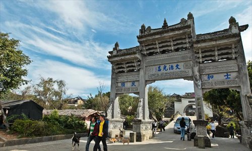 People walk under a stone archway in the ancient townlet Heshun in Tengchong County, southwest China's Yunnan Province, on November 3, 2012. The townlet, featuring time-honored temples and houses, is located three kilometers away from the county seat of Tengchong, where live 6,000 people. Photo: Xinhua