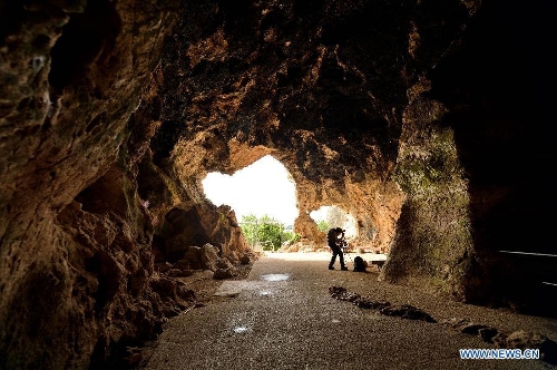 A tourist takes pictures of el-Wad Cave on the western slopes of the Mount Carmel range near Israeli northern city of Haifa on May 19, 2013. Sites of human evolution at Mount Carmel, including the caves of Tabun, Jamal, el-Wad and Skhul, were recognized as World Heritage Site by United Nations Educational, Scientific and Cultural Organization in 2012. (Xinhua/Yin Dongxun)
