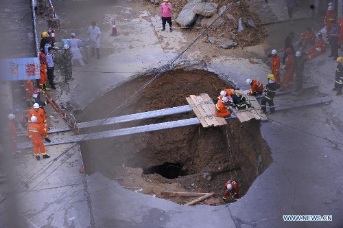 Rescuers work at the accident site where a road cave-in occurred in Huamao Industrial Park in Shenzhen, south China's Guangdong Province, May 21, 2013. The accident occurred around 9:19 p.m. (1319 GMT) on May 20. As of 4:30 p.m. (0830 GMT) Tuesday, 5 people were killed and another one injured as the cave-in led to a pit measuring three to four meters deep. Search and rescue efforts are under way. (Xinhua/Liang Xu) 